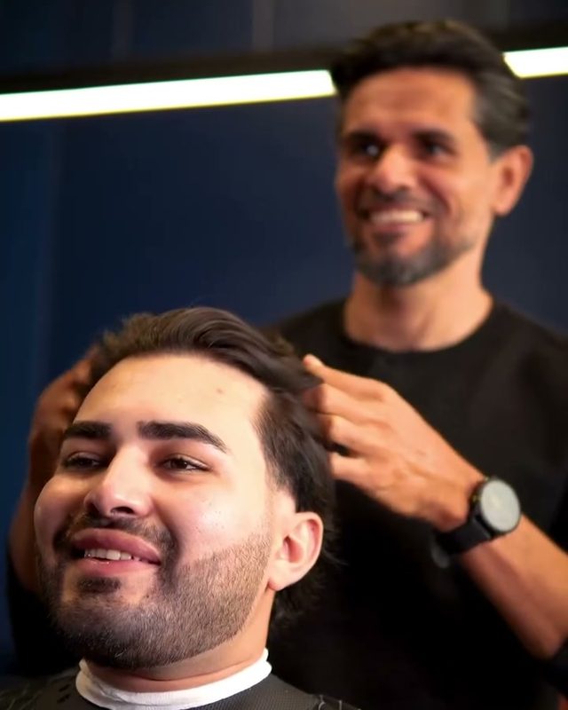 Barbeiro e cliente sorrindo depois do corte